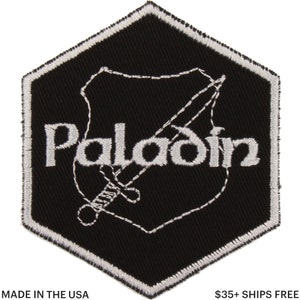 May include: Black and white embroidered patch featuring the word "Paladin" and a sword design. The patch has a hexagonal shape with a white border. The text "MADE IN THE USA" is at the bottom.
