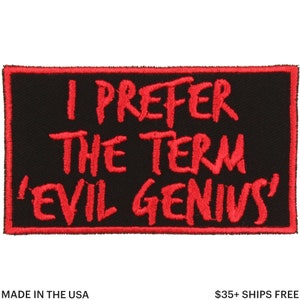 Puede incluir: Parche rectangular negro con texto bordado en rojo: "I PREFER THE TERM 'EVIL GENIUS'". El parche tiene un borde cosido en rojo y el texto "MADE IN THE USA".