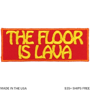 Puede incluir: Parche bordado con el texto "THE FLOOR IS LAVA" en amarillo sobre fondo rojo. El parche tiene un borde naranja y es de forma rectangular. Fabricado en EE. UU.