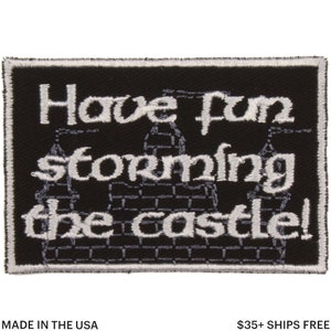 May include: Black rectangular patch with white embroidered text: "Have fun storming the castle!" A castle illustration is below the text. The patch is bordered with white stitching. Made in the USA.