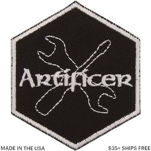 Puede incluir: Parche bordado en blanco y negro con forma hexagonal. El parche presenta la palabra "Artificer" en escritura blanca, con un diseño de llave inglesa cosida en blanco. El parche está bordeado con costuras blancas y tiene el texto "MADE IN THE USA" en la parte inferior.
