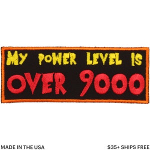 May include: A rectangular black patch with yellow and red embroidered text that reads "MY POWER LEVEL IS OVER 9000". The patch has an orange border and the text "MADE IN THE USA" is at the bottom.