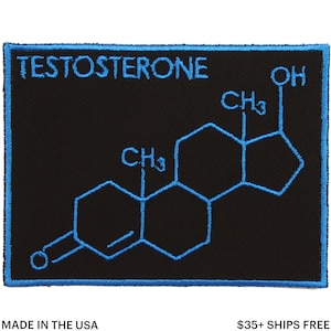 Może przedstawiać: Czarna, haftowana naszywka z niebieską obwódką. Zawiera napis "TESTOSTERONE" i diagram struktury molekularnej w kolorze niebieskim. Naszywka jest prostokątna.