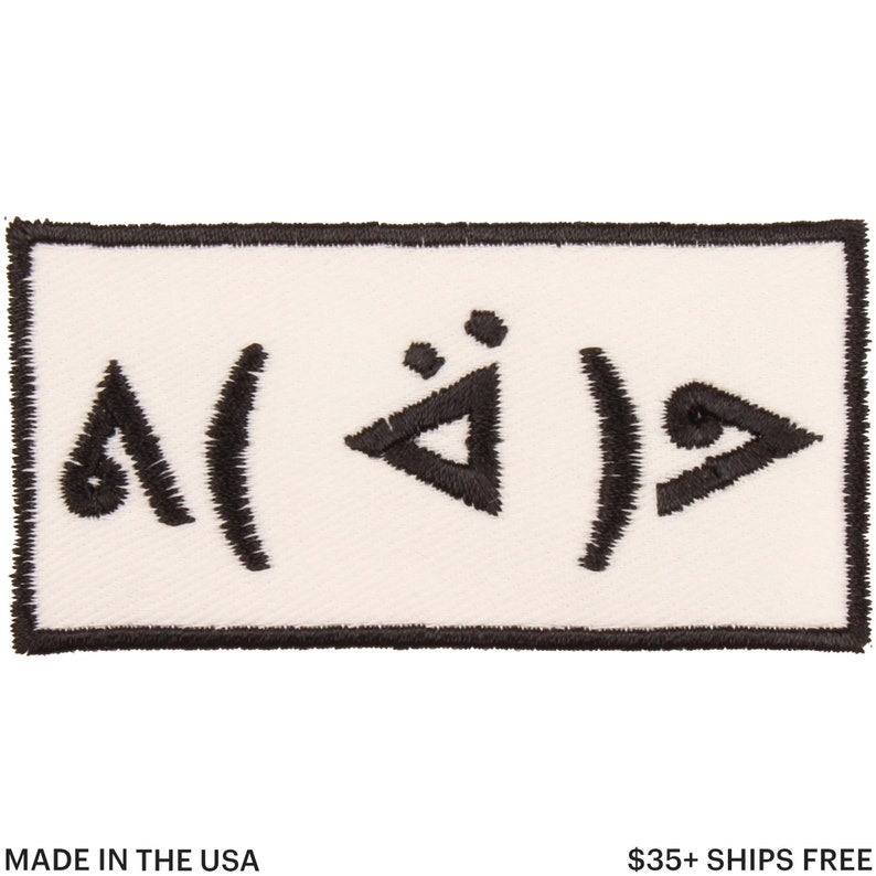 Pu&ograve; includere: Toppa rettangolare con sfondo bianco e disegno ricamato nero. Il disegno presenta simboli e forme astratte. La toppa ha un bordo nero e il testo "MADE IN THE USA" &egrave; in basso.