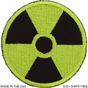 May include: Round, embroidered patch featuring a black radiation symbol on a bright green background. The patch has a stitched border and is suitable for application on clothing or accessories. The text "MADE IN THE USA" is at the bottom.