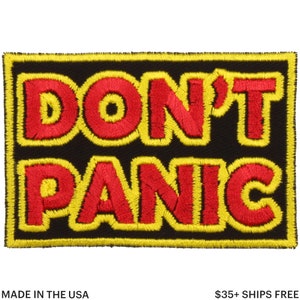 Könnte beinhalten: Rechteckiger, gestickter Aufnäher mit den Worten "DON'T PANIC" in Rot, gelb umrandet, auf schwarzem Hintergrund. Der Aufnäher hat einen gelben Rand. Der Text "MADE IN THE USA" steht unten.