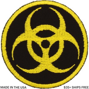 Könnte beinhalten: Runder, schwarzer Aufnäher mit einem gelben Biohazard-Symbol in der Mitte, umgeben von einem gelben Rand. Der Text "MADE IN THE USA" befindet sich unten links.