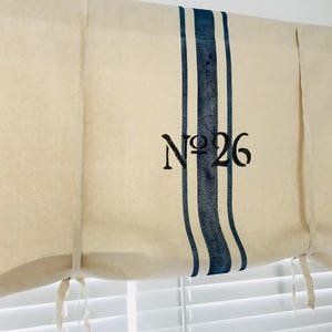 May include: White fabric roman shade with blue stripes and the text "No. 26" printed on it.