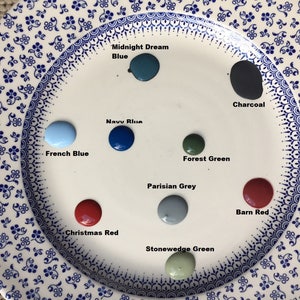May include: A white plate with paint samples in various colors, including Midnight Dream Blue, Navy Blue, French Blue, Forest Green, Parisian Grey, Stonewedge Green, Charcoal, Christmas Red, and Barn Red.