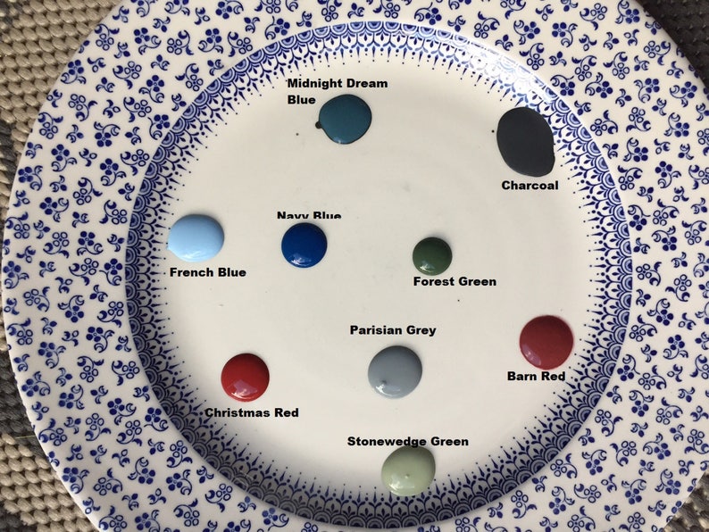 May include: A white plate with paint samples in various colors, including Midnight Dream Blue, Navy Blue, French Blue, Forest Green, Parisian Grey, Stonewedge Green, Charcoal, Christmas Red, and Barn Red.