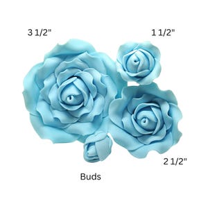 May include: A collection of light blue rose decorations in various sizes. The largest rose measures 3 1/2 inches, with others at 2 1/2 inches and 1 1/2 inches. There are also rose buds. These floral decorations are ideal for crafts and cake decorating.