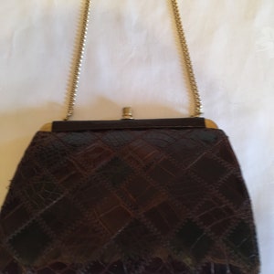 Puede incluir: Un bolso vintage marrón con un diseño de patchwork. El bolso presenta una correa de cadena y un cierre en tono dorado. El cuerpo del bolso está hecho de un material texturizado, posiblemente cuero o similar al cuero.