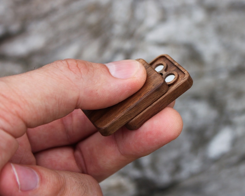 May include: A small wooden box with a hinged lid. The box has two circular openings on the top.