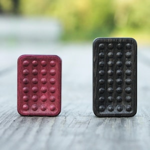 May include: Two wooden fidget toys, one red and one black, with a textured surface of small bumps.