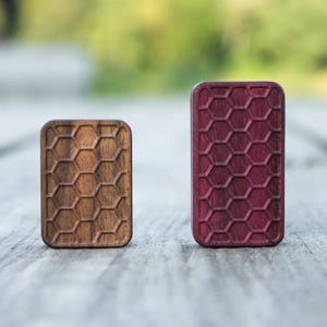 May include: Two wooden squares with a honeycomb pattern. The square on the left is brown and the square on the right is purple.