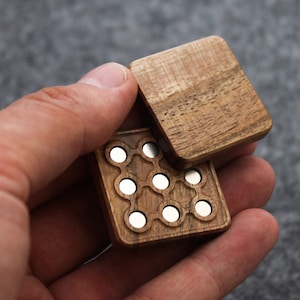 May include: A wooden box with a hinged lid, featuring a pattern of small, round, silver-colored metal circles. The box is made of dark wood with a natural grain.