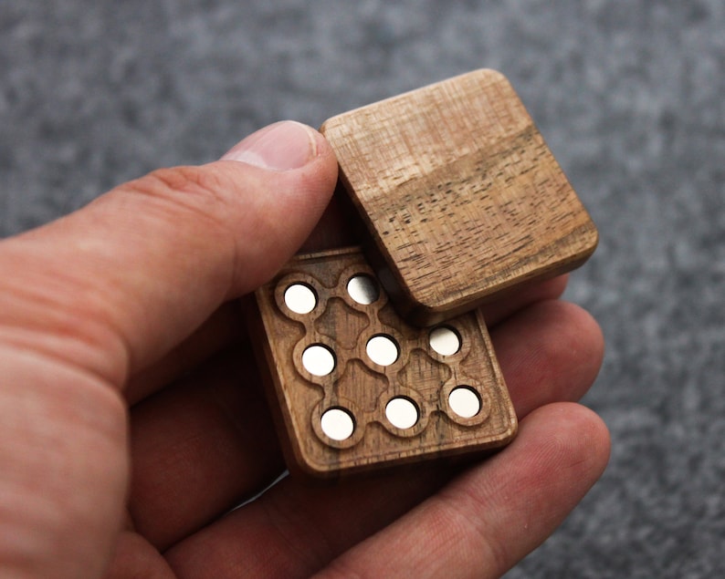 May include: A wooden box with a hinged lid, featuring a pattern of small, round, silver-colored metal circles. The box is made of dark wood with a natural grain.