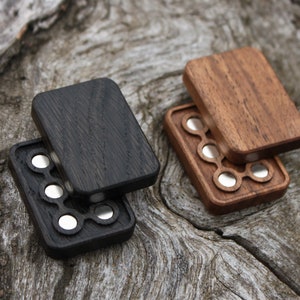 May include: Two wooden boxes with a hinged lid, each with a different wood grain. The boxes have a circular cutout pattern with silver metal circles inside.