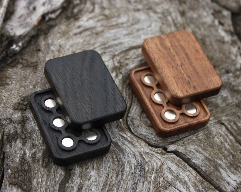 May include: Two wooden boxes with a hinged lid, each with a different wood grain. The boxes have a circular cutout pattern with silver metal circles inside.