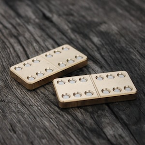 Può includere: Due domino di colore dorato con punti bianchi su una superficie di legno scuro.