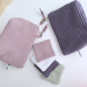 Könnte beinhalten: Zwei gefaltete Reißverschlusstaschen, eine in staubigem Rosa und eine in Dunkelgrau, mit einem weißen Etikett mit der Aufschrift "PRETTY IN MY", und drei gefaltete Tücher in Rosa, Weiß und Grün.