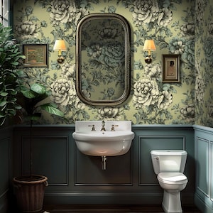 May include: A bathroom featuring floral wallpaper in green and cream tones. A white sink, toilet, and framed artwork are present. A large mirror and wall lights enhance the room's design. A potted plant is in the corner.