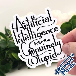 May include: A white die-cut sticker featuring black hand-lettered text that reads Artificial Intelligence is for the Genuinely Stupid. The sticker has a smooth, matte-like finish and a distinct, stylised font with decorative flourishes throughout the lettering.