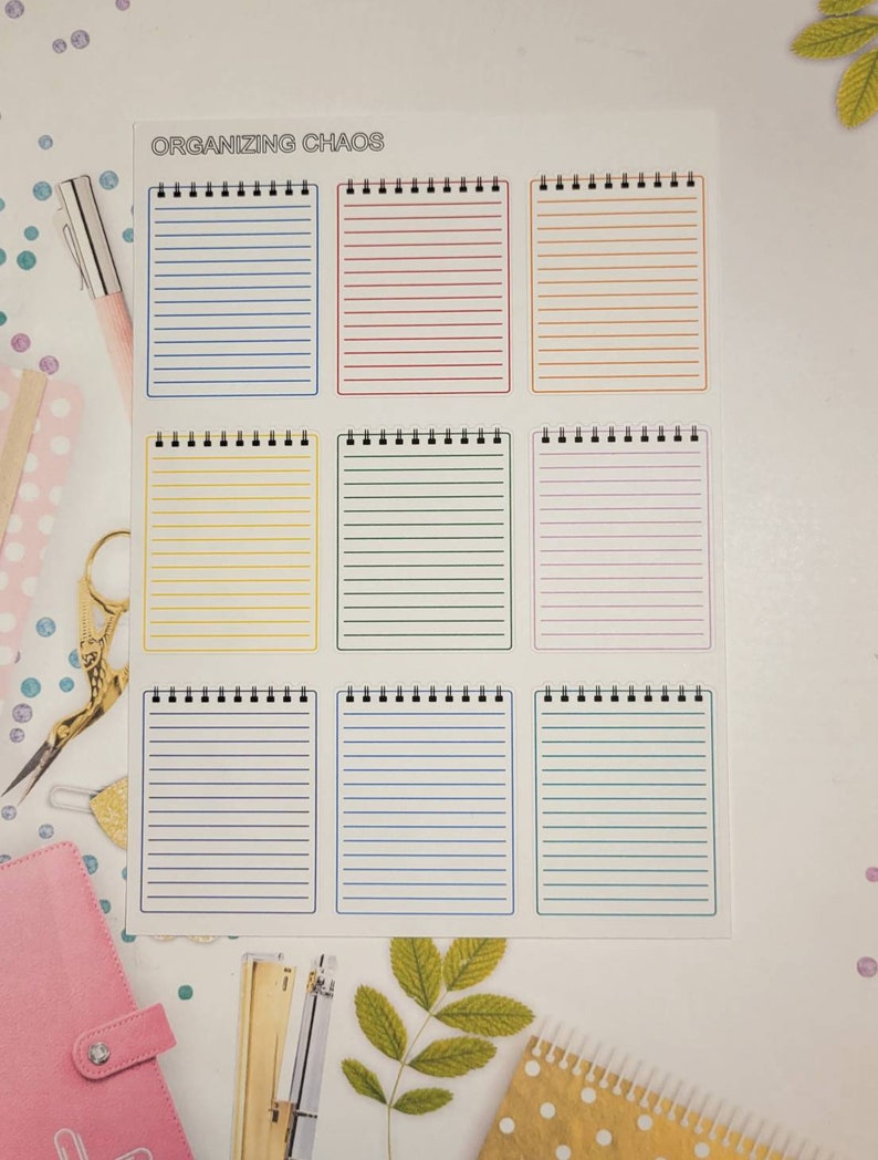 May include: A sheet of nine lined notepads in various colors, including blue, red, and yellow. The notepads are arranged in a grid pattern and bound with a black spiral. The text "ORGANIZING CHAOS" is printed at the top.