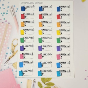 May include: A sheet of colorful planner stickers with the text "PLANNER Sub" and a dollar sign on each sticker. The stickers are in various colors, including blue, red, orange, yellow, green, purple, pink, and light blue.