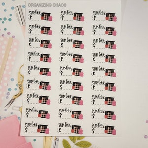 May include: A sheet of stickers with a black and white illustration of a makeup palette and a pink heart. The text "SUB BOX" and a dollar sign are printed on each sticker.