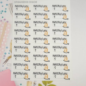 May include: A sheet of stickers with the text "ORGANIZING CHAOS" at the top. The stickers feature the Amazon Prime logo with the text "AMAZON Prime" and a dollar sign. The stickers are on a white background.