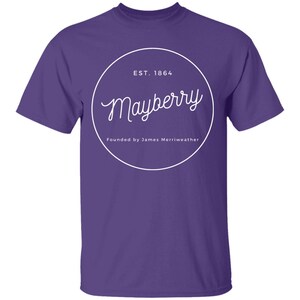 May include: Purple t-shirt with a white circle graphic that says "Mayberry" with the text "EST. 1864" and "Founded by James Merriweather" underneath.