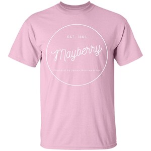 May include: Pink t-shirt with a white circle graphic that says "Mayberry" in a cursive font. The circle also says "EST. 1864" and "founded by  James Merriweather".