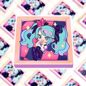 Può includere: Un adesivo quadrato con una ragazza dei cartoni animati in stile anime con capelli turchesi e un fiore rosa. La ragazza indossa un top bianco e pantaloni neri, su uno sfondo rosa e blu. L'adesivo ha un bordo rosa e scintille.