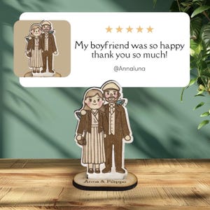 Puede incluir: Figura de madera de una pareja, el hombre con traje marr&oacute;n y la mujer con vestido. La base est&aacute; grabada con "Anna & Filippo". Una rese&ntilde;a de cliente dice "My boyfriend was so happy thank you so much!" con 5 estrellas.