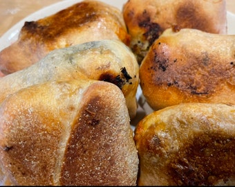 May include: Close-up of five golden brown, baked bread pockets. The pockets are slightly puffed and have a slightly crispy texture.