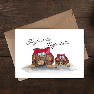 Op de afbeelding: Een witte kaart met een aquarel-illustratie van twee schildpadden met rode strikken en de tekst "Jingle shells... Jingle shells..."