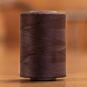 May include: A spool of dark brown thread.