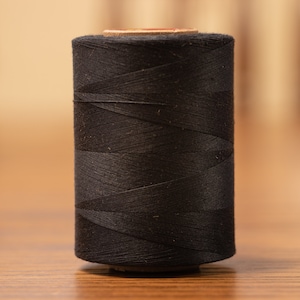 May include: A spool of black thread.
