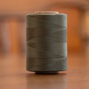 May include: A spool of dark green thread.