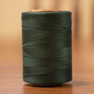 May include: A spool of dark green thread.