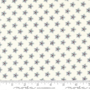 May include: White fabric with a repeating pattern of small blue and red stars. The fabric is marked with a ruler in inches and the words "moda" and "www.modafabrics.com".