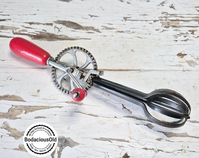 Vintage hand whisk with red wooden handle, retro kitchen tool