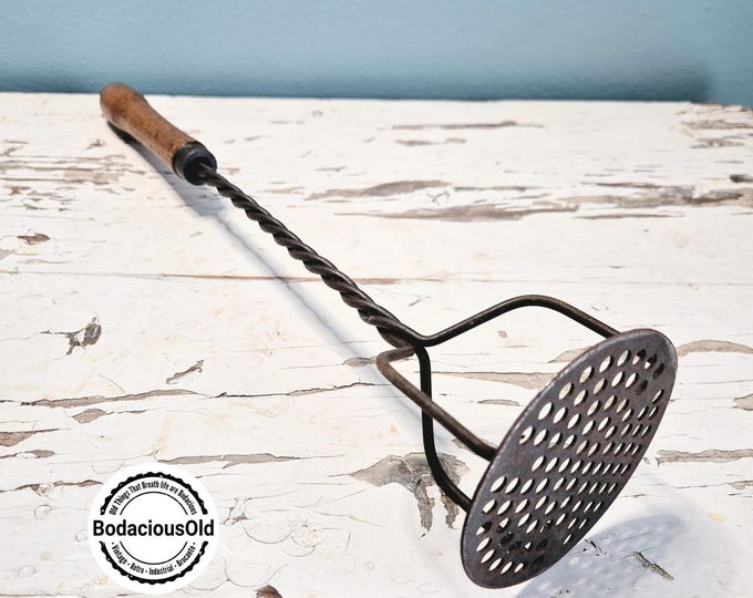 Vintage metal potato masher with wooden handle, rustic decorative kitchen tool