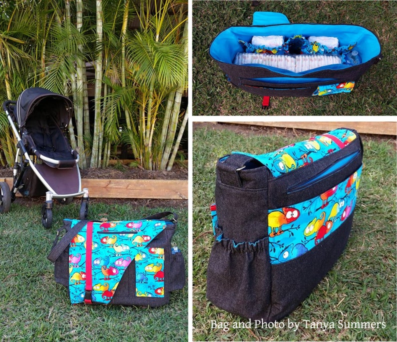 Op de afbeelding: Een zwarte luiertas met een kleurrijke kameleonprint. De tas heeft een groot hoofdvak, een ritsvak en een kleiner vak aan de voorkant. De tas wordt getoond met een kinderwagen op de achtergrond.