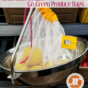 Pu&ograve; includere: Un sacchetto di rete bianco per prodotti con chiusura a coulisse gialla, pieno di frutta gialla, &egrave; appeso a una bilancia di metallo. Il sacchetto &egrave; etichettato "Go Green Produce Bags". &Egrave; attaccata una piccola etichetta gialla.