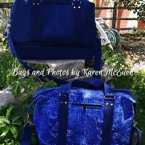 May include: Two blue canvas duffel bags. The top bag is solid blue. The bottom bag has a white and blue geometric pattern. Both bags have a zippered pocket on the front and a top handle.