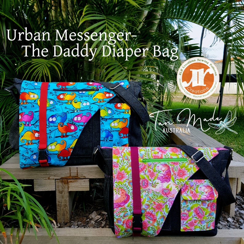 Op de afbeelding: Twee luiertasjes, een met een blauwe en groene kameleonprint en de andere met een roze en groene bloemenprint. Beide tassen hebben zwarte denim accenten en verstelbare banden. De tassen zijn gelabeld "Urban Messenger - The Daddy Diaper Bag" en "Tom Made Australia".