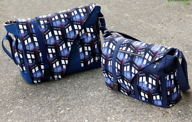 Op de afbeelding: Twee blauwe messenger bags met een wit en blauw patroon met een herhalend beeld van een politiebak. De grotere tas heeft een zwarte band en de kleinere tas heeft een zilveren rits.