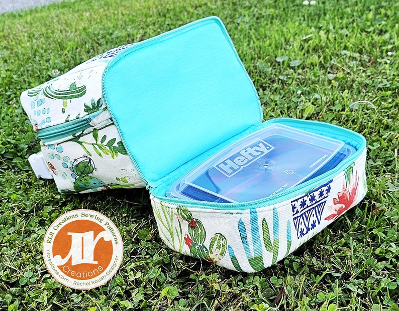 Puede incluir: Una bolsa de almuerzo blanca con estampado de cactus y forro turquesa. La bolsa est&aacute; abierta y contiene un recipiente de pl&aacute;stico transparente Hefty.